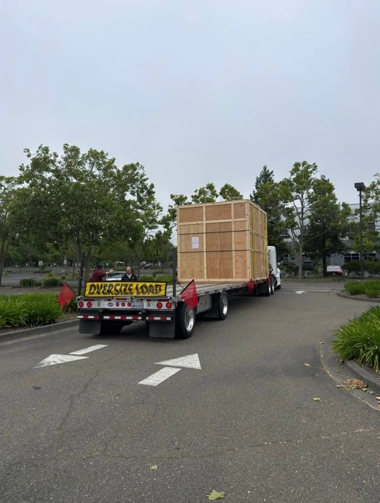 Oversize crated load seen from behind with warning banner